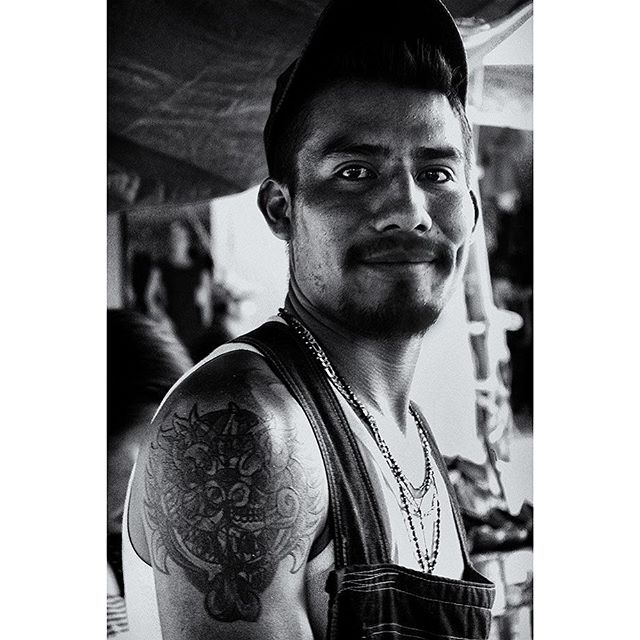 PORTRAIT - FACES OF MEXICO

In Mexico, many people shy away from the camera at the markets. This guy was the exception. He caught my attention and motioned for me to take his picture. He wanted to show his tattoo because he stood with his right shoulder facing me. 
The dragon symbol is one of strength and protection. That he has it on his right shoulder, possibly points to his status as the head of his family, probably the breadwinner. He is younger than the average market vendor, especially the food vendors. 
One can sense his gentle pride in the photo. This is what makes it special for me. 
#oaxaca #tlacolula #mexico #mexican #market #dragon #dragontattoo #tattoo #protector #headofthefamily #bw #portrait #oldschool #spiro #spirophotographer #spiro_photographer